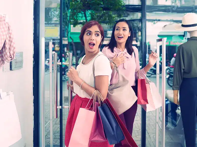 women walking into retail store smiling surprised